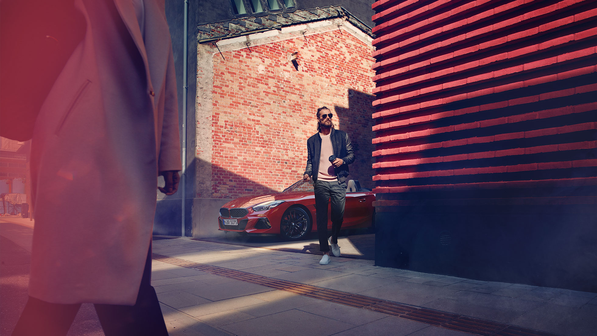 Man in a side street in front of BMW Z4 Roadster BMW Z4 Roadster in side street